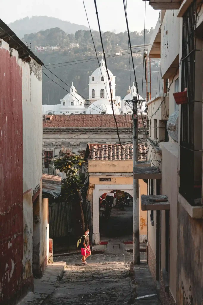 A view of a traditional street in Quetzaltenango, with a church and mountains in the background
